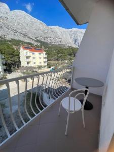 a balcony with a table and chair and mountains at Apartments Jurisic in Baška Voda