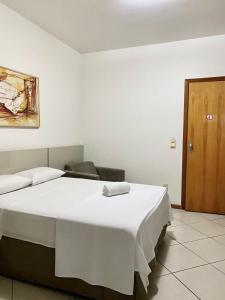 um quarto com uma grande cama branca e uma porta de madeira em Manferrari Hotel em Contagem