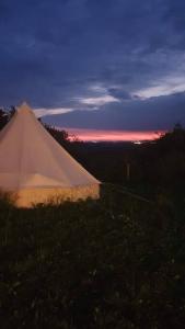 a white tent with a sunset in the background at French Tent secret garden glamping in Newark-on-Trent