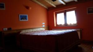 una camera da letto con pareti arancioni e un letto con finestra di Casa Rural el Casillo del Abuelo Goyo a Navarredonda de Gredos