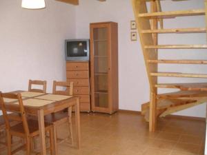 una sala da pranzo con un tavolo, una televisione e una scala di Domki letniskowe Pod brzozą a Nowęcin