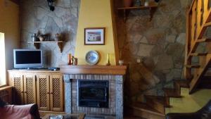 sala de estar con chimenea y TV en Casa Rural el Casillo del Abuelo Goyo, en Navarredonda de Gredos