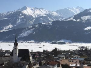 a small town with a church and snow covered mountains at Glas House - Design Holiday Home in Piesendorf