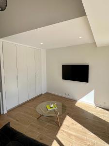 ein Wohnzimmer mit einem TV und einem Tisch in der Unterkunft Superbe studio avec accès mer. in Le Pradet