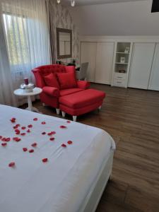 a bedroom with a bed and a red couch and roses on the bed at Hotel Restaurant Keizersberg in Elsendorp