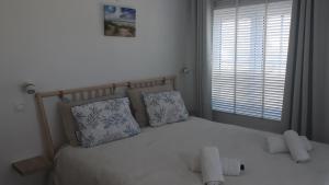 um quarto com uma cama branca com almofadas e uma janela em Residentie Lenthe em De Haan