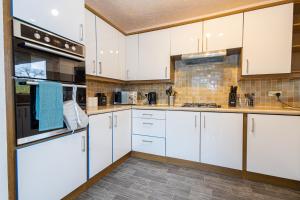una cocina blanca con armarios y electrodomésticos blancos en M9 Guest House, en Mánchester