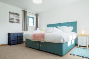 a bedroom with a large bed with a blue headboard at Kerensa in Mawnan
