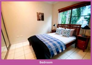 - une chambre dotée d'un lit avec une couverture tressée et une fenêtre dans l'établissement Magic On Melton, à Townsville