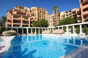 a swimming pool with chairs and buildings in the background at Studio à Monaco Fontvieille in Monte Carlo