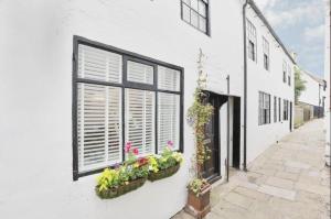 a white building with two windows with flowers on it at Whitby Boutique - Mast Cottage in Whitby