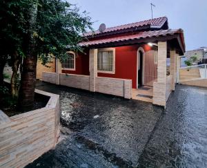 una casa roja con un árbol delante en Casa com piscina e Wi Fi em Mongagua SP, en Praia Grande