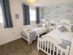 two white cribs in a bedroom with blue curtains at The Coach House in Newport