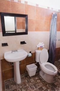 a bathroom with a toilet and a sink and a mirror at Hotel Makarios in Tuxtla Gutiérrez