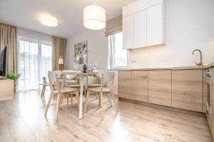 a kitchen and dining room with a table and chairs at Apartament o2 ALLDAYHOLIDAY Mielno in Mielno