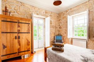 una camera da letto con pareti in pietra, un letto e una sedia di Casa do Cabeço a Caramulo