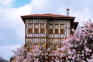 a building with pink flowering trees in front of it at Meymune Valide Konağı in Safranbolu