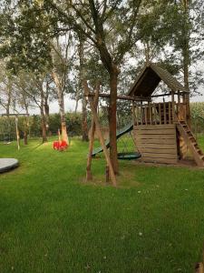 un parque infantil con un árbol y un tobogán en Vakantiewoning 't Veurhuus en Bergentheim