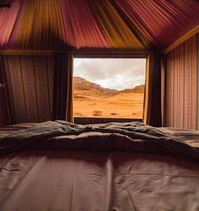 a bedroom with a view of the desert from a window at Wadi Rum Red Sand Camp in Wadi Rum