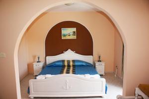 a bedroom with a white bed in an archway at Family Hotel Paros 2 in Pomorie