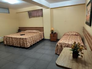 a hotel room with two beds and a table at Hotel Olaya in Lima