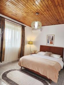 um quarto com uma cama grande e um tecto de madeira em Mia Guest House - Entire home with balcony & garden em Divjakë