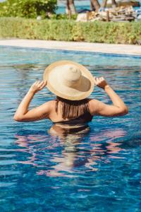 a woman wearing a hat in a swimming pool at Ixchel Beach Hotel in Isla Mujeres
