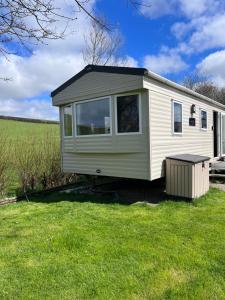 a small white caravan in a field of grass at Newquay Caravan, Newquay Bay Resort Jetts View 104 in Newquay