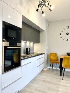 una cucina con armadi bianchi e un orologio sul muro di Apartamenty Planeta - Koszalin a Koszalin