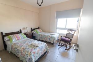 een slaapkamer met 2 bedden, een stoel en een raam bij Departamento vista al rio 2 dormitorios, dos baños. Amplio y moderno in Posadas