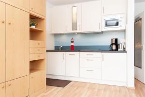 a kitchen with white cabinets and a red fire hydrant at Haus Hanseatic, Wohnung 204 in Duhnen