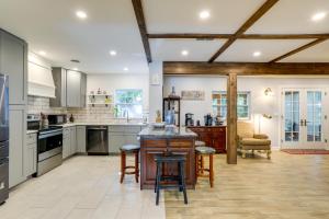a kitchen with white cabinets and a island with bar stools at Charming Home with Yard about 5 Mi to Clearwater Beach! in Clearwater