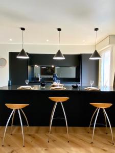 una cucina con bancone nero e 2 sgabelli di Guethary superbe appartement centre proche plage a Guéthary
