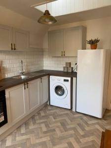a kitchen with a white refrigerator and a washing machine at Centrally located flat with parking in Tetbury