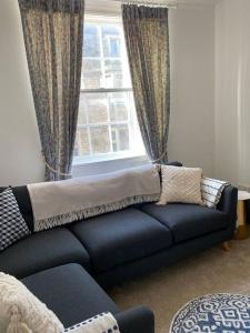 a living room with a couch in front of a window at Centrally located flat with parking in Tetbury