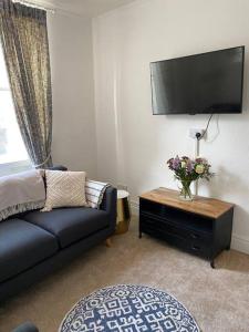 a living room with a couch and a table with a tv at Centrally located flat with parking in Tetbury