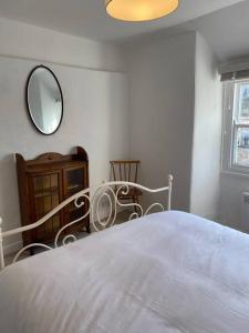 a bedroom with a white bed and a mirror at Centrally located flat with parking in Tetbury