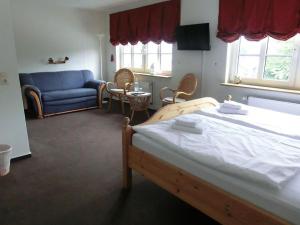 ein Schlafzimmer mit einem Bett und einem blauen Sofa in der Unterkunft Landquartier in Schwesing