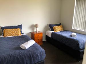 ein Schlafzimmer mit 2 Betten und einem Nachttisch mit einer Lampe in der Unterkunft Twizel - Apartment on Woodley in Twizel