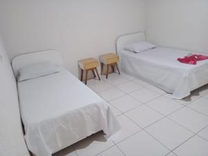 two beds in a white room with two chairs at Hotel Novo Algés in Sao Paulo