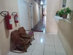 um corredor com um extintor de incêndio e duas cadeiras em Hotel Novo Algés em São Paulo