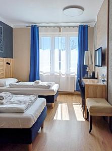 a hotel room with two beds and a desk and a window at Kamienica Morska Gdynia in Gdynia