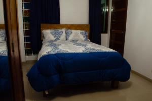 1 dormitorio con 1 cama con edredón y almohadas azules en Irene's House, en Lima