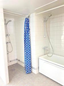 uma casa de banho com uma cortina de chuveiro azul e uma banheira em Tallkrogen Romantic House - Upper or Lower Apartment em Estocolmo