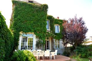 a table and chairs in front of a building with ivy at Villa Château Gontier in Château-Gontier