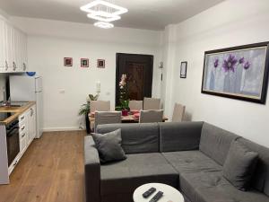 a living room with a gray couch and a kitchen at Arteg Apartments - Premium in Durrës