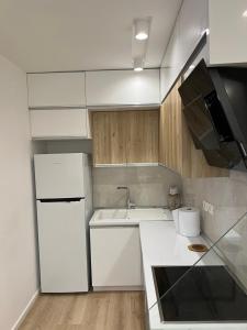 La cuisine blanche est équipée d'un évier et d'un réfrigérateur. dans l'établissement Beach apartment, à Durrës