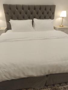 uma grande cama branca com uma cabeceira cinzenta e almofadas brancas em أستراحة مون لايت الريفي em Al-ʿUla