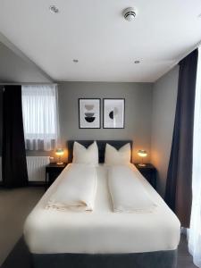 a bedroom with a large white bed with two lamps at mala me Hotel in Hannover