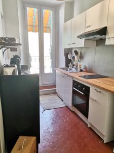 eine Küche mit weißen Schränken und einem roten Boden in der Unterkunft Appartement cozy au cœur du village in Roquebrune-sur-Argens